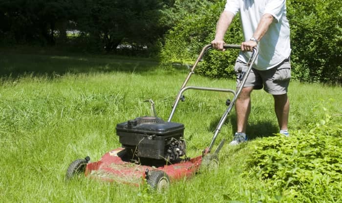 man cutting weeds and grass with a lawnmower